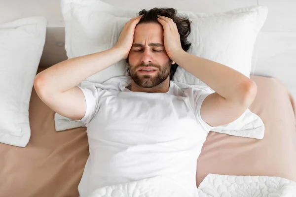 Restless young man waking up with headache — Stock Photo, Image
