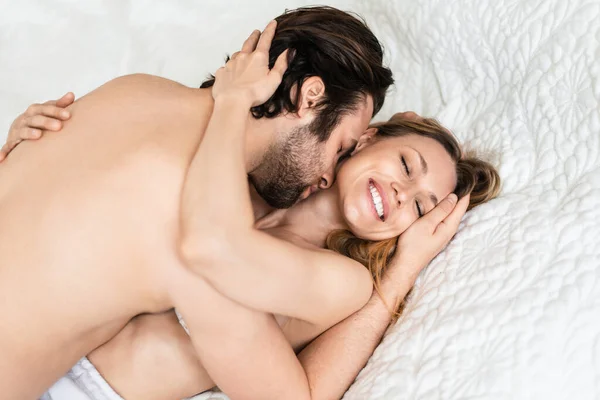 Tutkulu genç çift yatakta sevişiyor, öpüşüyor ve sarılıyor. — Stok fotoğraf