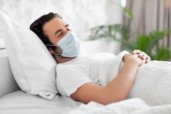 Homem doente na máscara facial sofrendo de vírus na cama — Fotografia de Stock