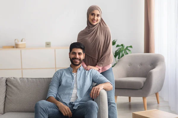 Iszlám férj és feleség mosolygós áll a modern nappaliban — Stock Fotó
