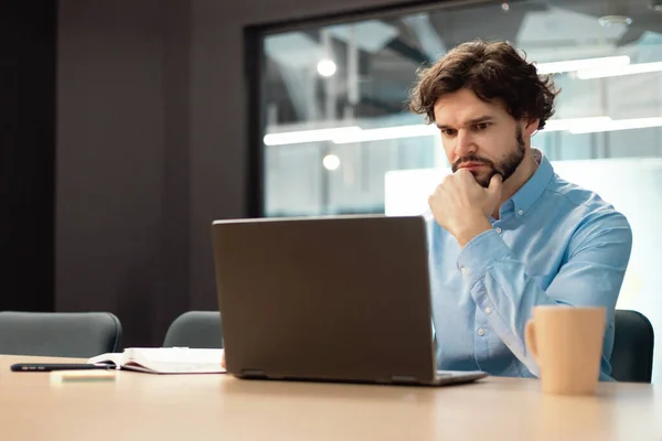 Focused man using laptop sitting at desk in office — Foto Stock