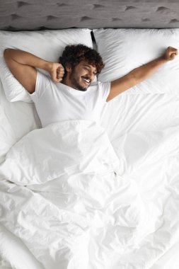 Mutlu Hindu adam sabahları yatakta geriniyor.