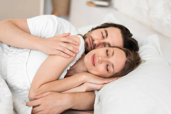 Amar joven pareja tener acogedor mañana, abrazos juntos en su sueño en la cama — Foto de Stock