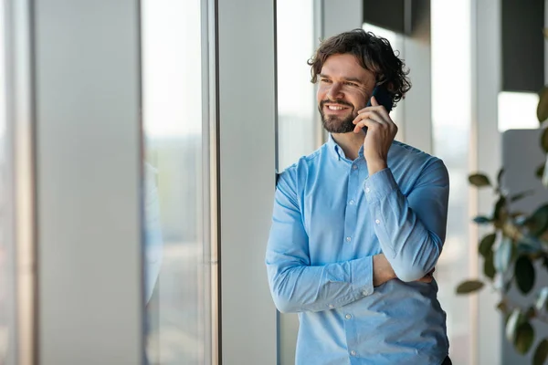 Smiling business man working and talking on phone at office — Stock Photo, Image