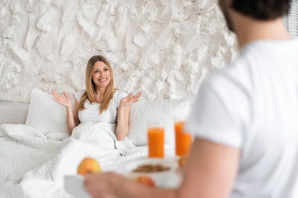 Romantic millennial guy bringing breakfast to bed for his girlfriend at home — Stock Photo, Image