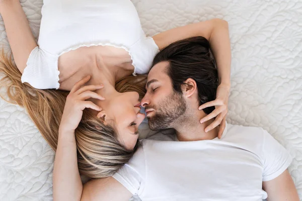 Κάτοψη της αγάπης ζευγάρι χιλιετή κοιμάται στο κρεβάτι, αγγίζοντας τα χείλη και αγκαλιές. Έννοια της αγάπης και των σχέσεων — Φωτογραφία Αρχείου