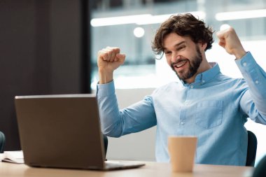 Excited businessman using pc celebrating success shaking fists screaming yes