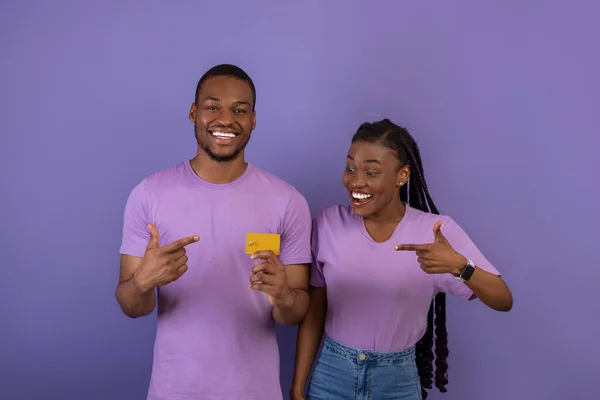 Glückliches schwarzes Paar, das Kreditkarte hält und zeigt — Stockfoto