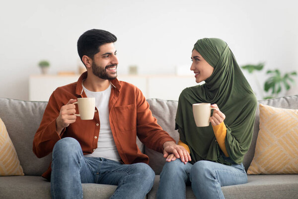 Cheerful Muslim Spouses Drinking Coffee Together Sitting At Home