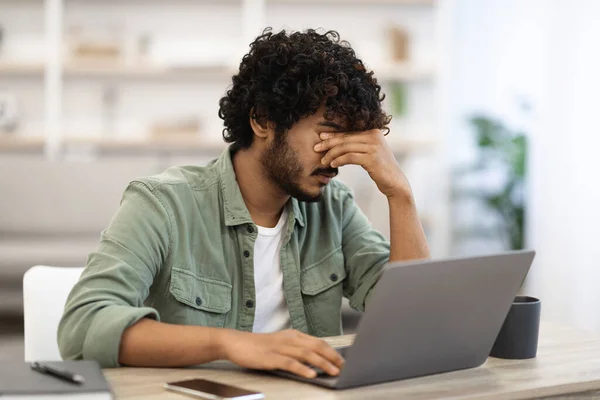 Fáradt sötét bőrű fickó ül workdesk előtt laptop — Stock Fotó