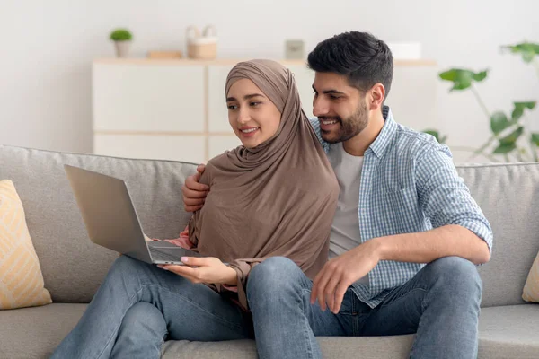 Contented Islamic Couple Browsing Internet On Laptop Computer At Home — стоковое фото