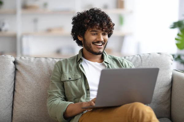 Relaxed dark-skinned guy using notebook at home — Foto de Stock
