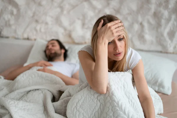 Unhappy woman sitting on bed, suffering from her boyfriends snoring, feeling dissatisfied because of sexual problems — Stockfoto