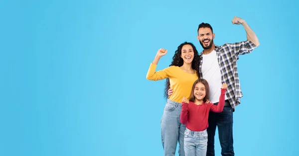 Família árabe feliz mostrando bíceps em pé sobre fundo de estúdio azul — Fotografia de Stock