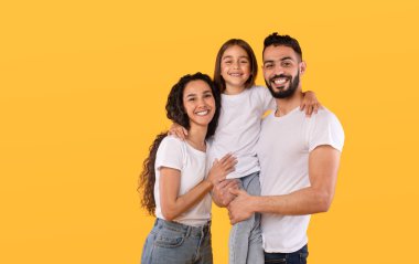 Arap Ebeveynler ve Kız Kucaklıyor Sarı Arkaplanda Birlikte Poz Veriyorlar