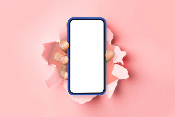 Osoba zobrazující bílou prázdnou obrazovku smartphonu prolamující papír — Stock fotografie