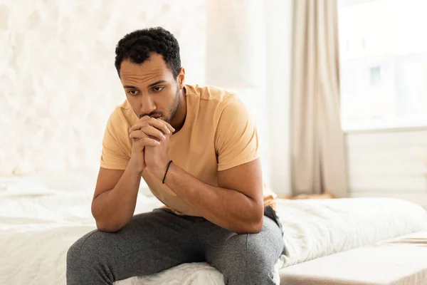 Depresivní muž ze Středního východu sedí a přemýšlí v moderní ložnici — Stock fotografie