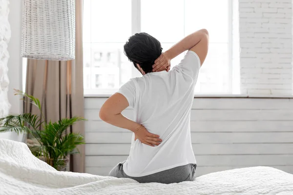 Unrecognizable man suffering from back pain at home in bedroom — Stock Photo, Image