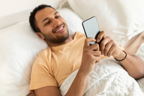 Cheerful Middle Eastern Man Using Cellphone In Bedroom, Selective Focus — стоковое фото