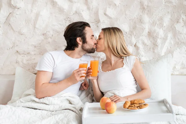 Amare la giovane coppia che fa colazione a letto insieme, baciare, trascorrere la luna di miele in hotel — Foto Stock