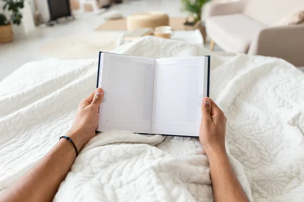 Man Holding Business Planner Planning Day Lying In Bedroom, POV — Zdjęcie stockowe