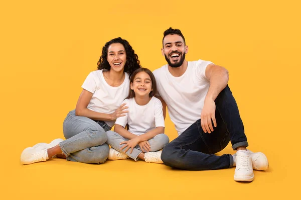 Alegre família do Oriente Médio de três sentados em fundo amarelo — Fotografia de Stock