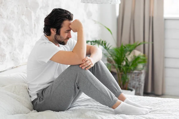 Unhappy millennial man feeling down, bedroom interior — Stock Photo, Image