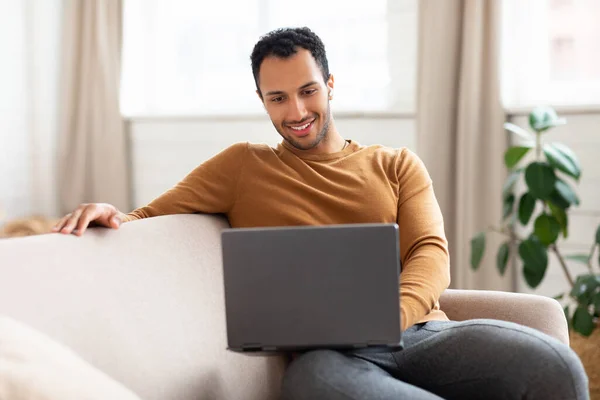 Arabische man met laptop zittend op bank thuis — Stockfoto