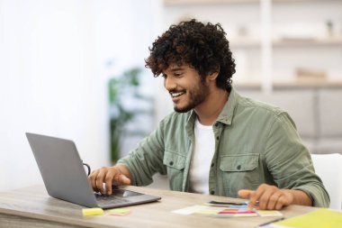 Bilgisayarda çalışan mutlu Hintli adam, ofis içi.