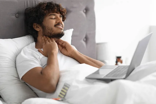 Hombre enfermo sentado en la cama, llamando al médico por computadora portátil — Foto de Stock
