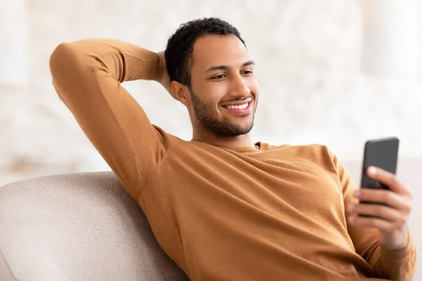 Retrato del hombre árabe sonriente usando un teléfono inteligente en casa — Foto de Stock