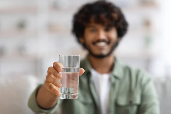 Koyu tenli bir adam bir bardak su gösteriyor ve gülümsüyor. — Stok fotoğraf