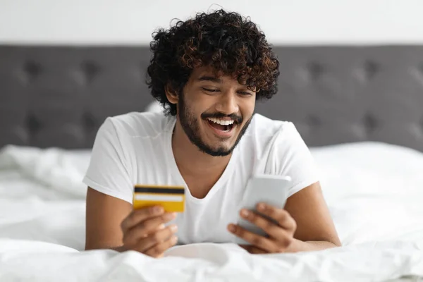 Positive hindu man using smartphone and credit card — Stock fotografie