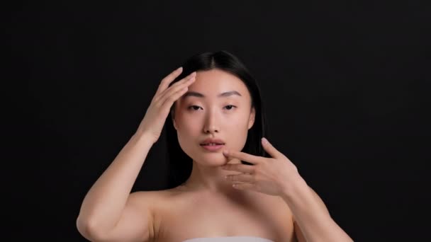 Perfect skin concept. Beauty portrait of young asian lady caressing her face, enjoying skin condition, looking at camera — Stock Video