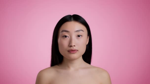 Natural asian beauty. Attractive korean woman with bare shoulders posing and smiling to camera, pink studio background — Stok video