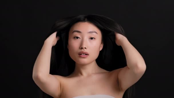 Zdravý a silný účes. Mladá krásná asijská žena třást vlasy, demonstrující sílu, černé pozadí — Stock video