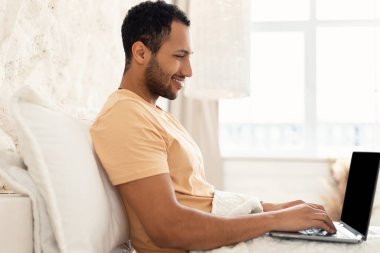 Yatak odasında çalışan dizüstü bilgisayar kullanan Mutlu Serbest Çalışan Adam