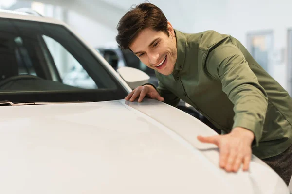 Positive millennial Caucasian guy touching new white car, selecting automobile at dealership store, copy space — Stock Fotó