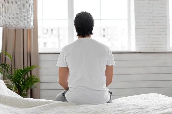 Αγνώριστος άντρας με πιτζάμες που κάθεται στο κρεβάτι το πρωί — Φωτογραφία Αρχείου