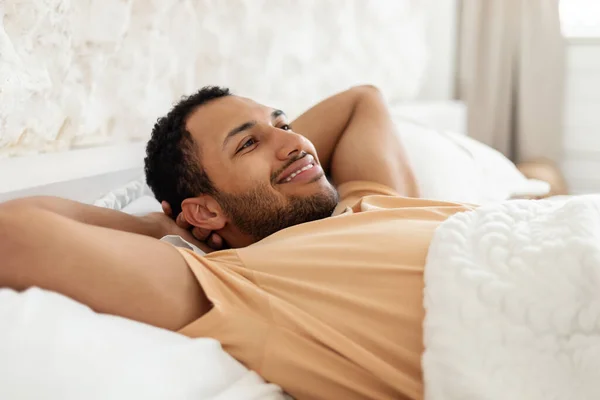 居心地の良いベッドルームで寝そべってリラックスして幸せな中東の男 — ストック写真