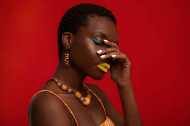 Şık kısa saçlı siyahi kadın kırmızı üzerine poz veriyor.