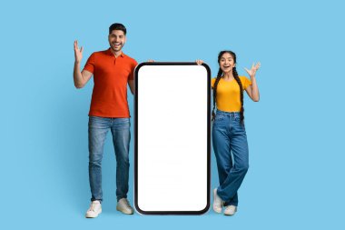 Surprised Arab Couple Standing Near Big Blank Smartphone And Exclaiming With Excitement