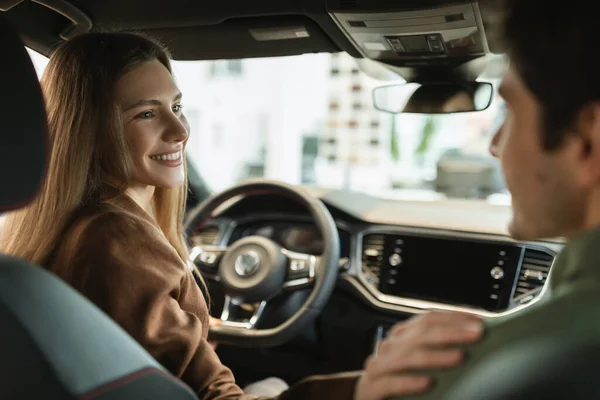 Happy young Caucasian spouses buying new car, doing test drive, sitting inside modern auto at dealership, free space — Stockfoto