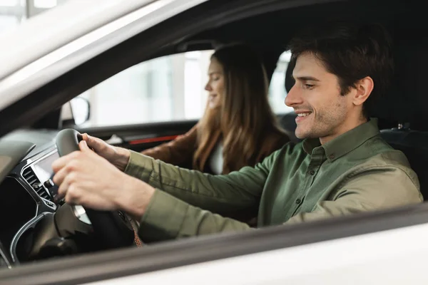 Cheerful young Caucasian couple test driving new car at auto dealership, copy space — 스톡 사진