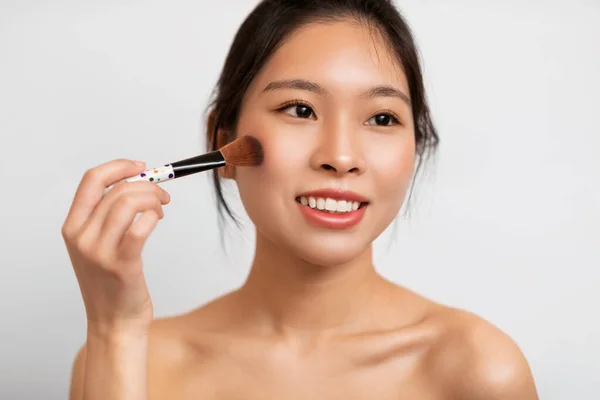 Portrait of beautiful Asian woman with makeup brush — Foto de Stock
