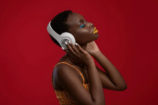 Memnuniyetle Afro-Amerikalı bayan, kırmızıda kablosuz kulaklık kullanıyor. — Stok fotoğraf