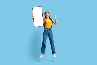 Online Offer. Overjoyed Young Arabic Woman Jumping With Big Blank Smartphone