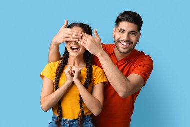 Yakışıklı, genç bir Arap kız arkadaşının gözlerini elleriyle kapatıyor ve tahmin et kim oynuyor?