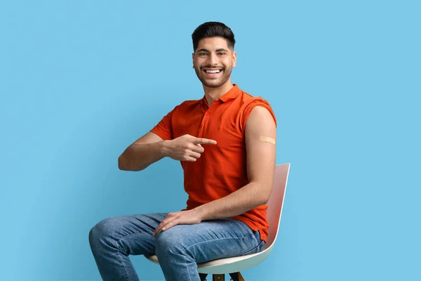 Immunization Campaign. Smiling Middle Eastern Guy Pointing At Adhesive Band On Shoulder — стоковое фото