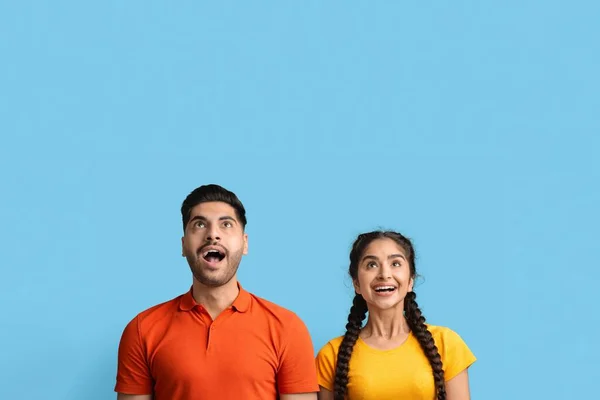 Sorprendido joven pareja de Oriente Medio mirando hacia arriba en el espacio de copia con emoción —  Fotos de Stock